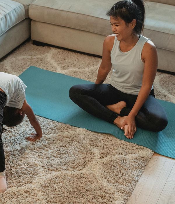 A child laughing while trying a tree yoga pose, showing balance and fun.